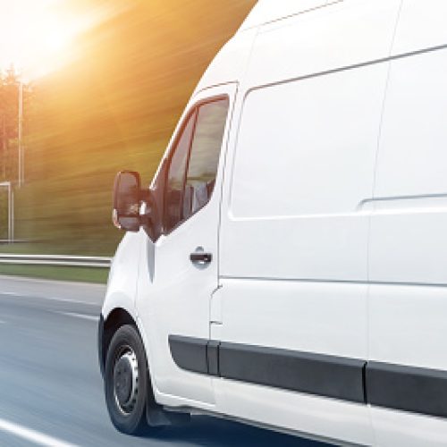 White modern delivery small shipment cargo courier van moving fast on motorway road to city urban suburb. Busines distribution and logistics express service. Mini bus driving on highway day. banner.