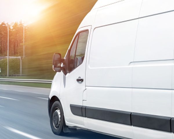 White modern delivery small shipment cargo courier van moving fast on motorway road to city urban suburb. Busines distribution and logistics express service. Mini bus driving on highway day. banner.